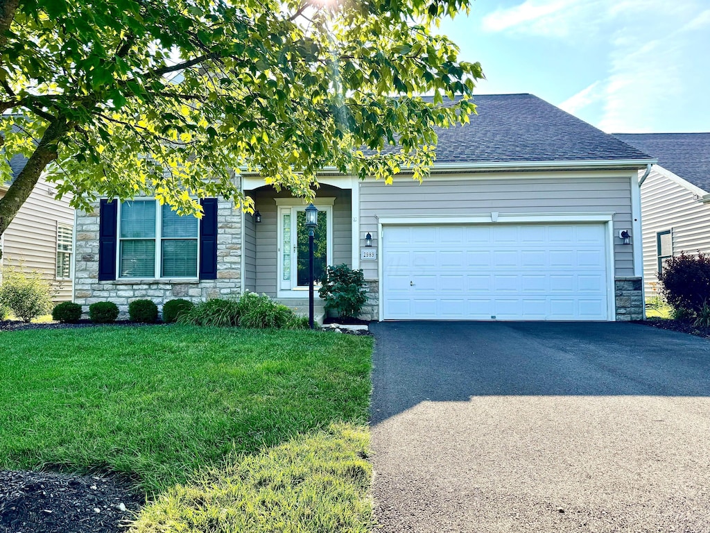 2989 Tree Bend Cir, Grove City, OH 43123 - view of property hidden behind natural elements featuring stone siding, asphalt driveway, a shingled roof, a garage, and a front lawn