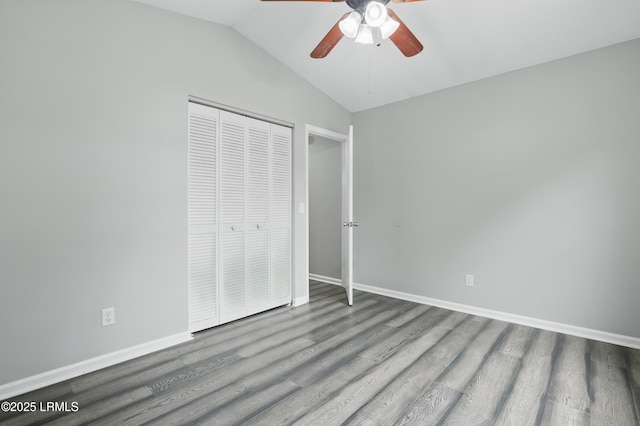 unfurnished bedroom with wood finished floors, lofted ceiling, a closet, baseboards, and a ceiling fan