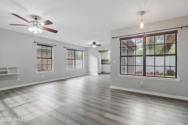 unfurnished living room featuring a ceiling fan, wood finished floors, and baseboards