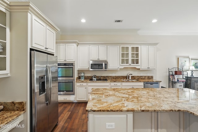 27 Normandy Ave, Bluffton, SC 29910 - kitchen featuring appliances with stainless steel finishes, crown molding, glass insert cabinets, light stone countertops, and dark wood-type flooring