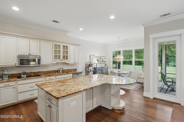 27 Normandy Ave, Bluffton, SC 29910 - kitchen with appliances with stainless steel finishes, a kitchen island, dark wood-style flooring, crown molding, and light stone countertops