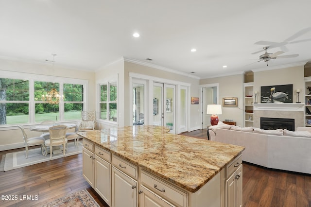 27 Normandy Ave, Bluffton, SC 29910 - kitchen featuring cream cabinetry, dark wood-style floors, light stone counters, ornamental molding, and a glass covered fireplace