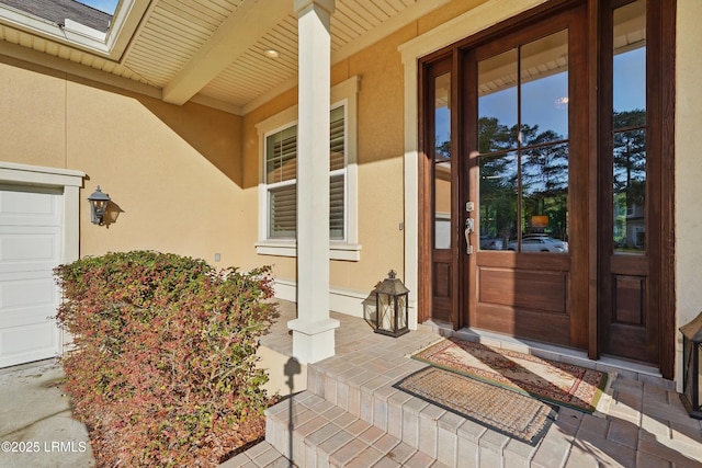 27 Normandy Ave, Bluffton, SC 29910 - doorway to property with stucco siding, covered porch, and a garage
