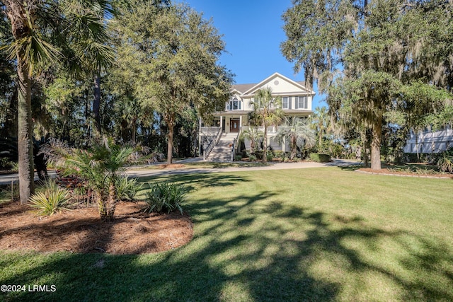 view of front of home featuring covered porch, stairway, and a front lawn