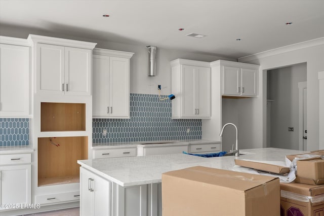 1 Alumni Rd, Beaufort, SC 29907 - kitchen with decorative backsplash, white cabinetry, a center island with sink, and a sink
