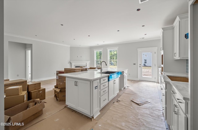 1 Alumni Rd, Beaufort, SC 29907 - kitchen featuring a fireplace, light countertops, ornamental molding, white cabinetry, and an island with sink
