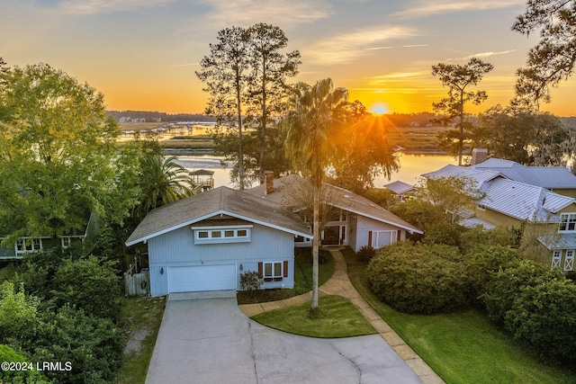 view of front facade with a garage, a water view, and a yard