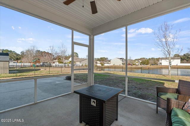 unfurnished sunroom with ceiling fan and a water view