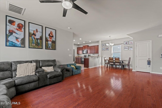 living room featuring ceiling fan with notable chandelier and dark hardwood / wood-style floors