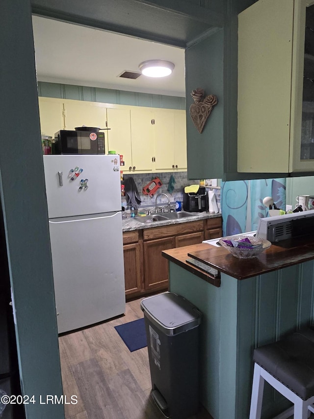 kitchen featuring tasteful backsplash, white fridge, sink, and light wood-type flooring