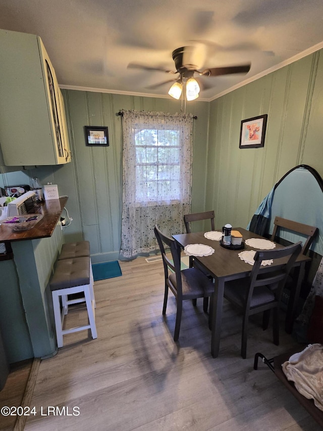 dining room with ceiling fan, ornamental molding, and light hardwood / wood-style floors