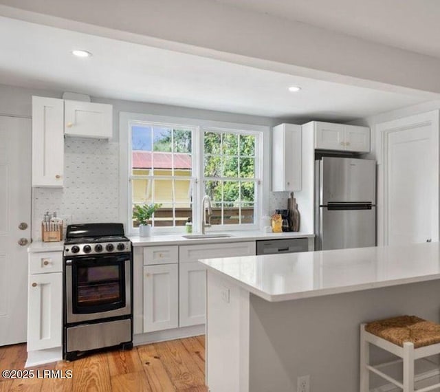 606 Carteret St Unit 2, Beaufort, SC 29902 - kitchen featuring light wood-style flooring, white cabinets, appliances with stainless steel finishes, a sink, and light countertops