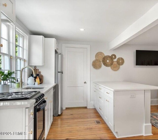 606 Carteret St Unit 2, Beaufort, SC 29902 - kitchen with a sink, light countertops, freestanding refrigerator, black range oven, and white cabinetry