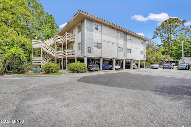 view of building exterior featuring stairs and uncovered parking