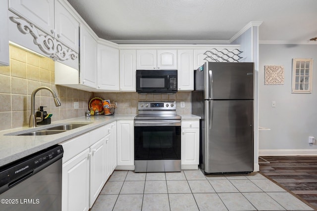 kitchen with a sink, stainless steel appliances, decorative backsplash, crown molding, and white cabinets