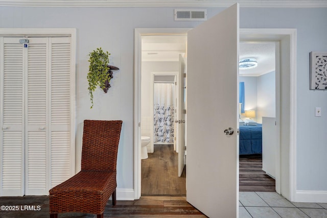 living area featuring crown molding, visible vents, wood finished floors, and baseboards