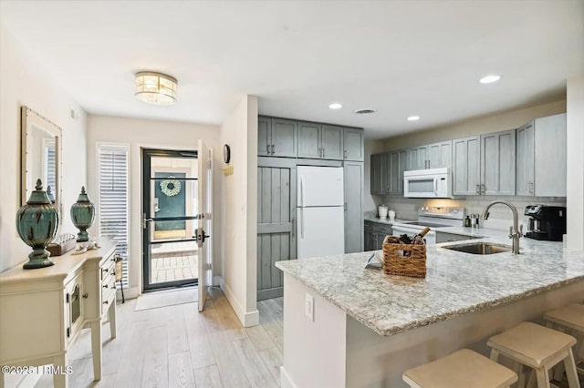 45 Queens Folly Rd Unit 794, Hilton Head Island, SC 29928 - kitchen with white appliances, gray cabinetry, a peninsula, light stone counters, and light wood-style flooring