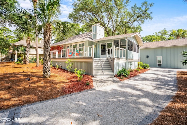 106 Sand Piper Run, Fripp Island, SC 29920 - view of front facade with a sunroom, stairs, a chimney, and driveway