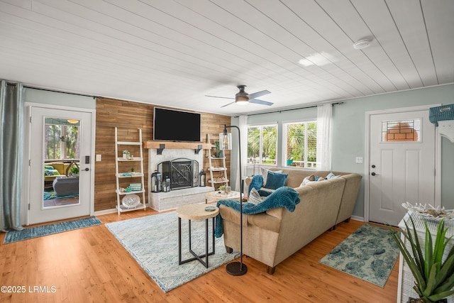 106 Sand Piper Run, Fripp Island, SC 29920 - living area with healthy amount of natural light, a fireplace, wood walls, ceiling fan, and light wood-style flooring