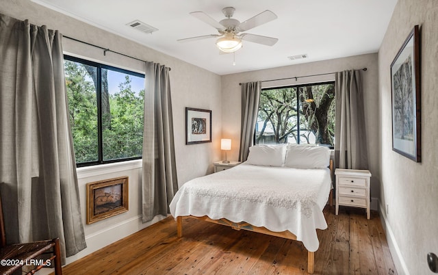 bedroom featuring multiple windows, hardwood / wood-style flooring, and ceiling fan