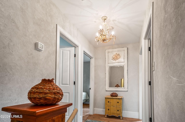 hallway featuring wood-type flooring and a notable chandelier