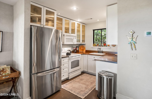 kitchen featuring butcher block countertops, sink, white appliances, and white cabinets