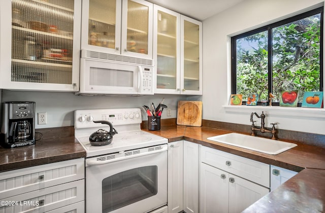 kitchen featuring white cabinetry, sink, and white appliances