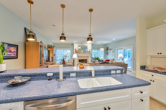 1120 Palmetto Pt, Dataw Island, SC 29920 - kitchen with stainless steel dishwasher, white cabinets, a glass covered fireplace, pendant lighting, and open floor plan