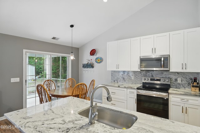 29 Wiregrass Way, Bluffton, SC 29910 - kitchen with stainless steel appliances, a sink, vaulted ceiling, decorative backsplash, and white cabinets