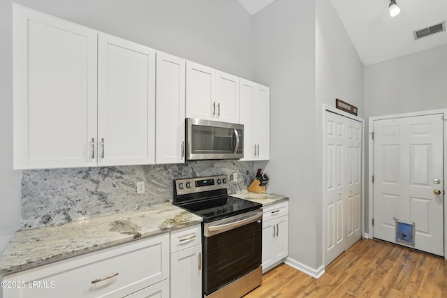 29 Wiregrass Way, Bluffton, SC 29910 - kitchen with stainless steel appliances, lofted ceiling, backsplash, white cabinets, and light wood-type flooring