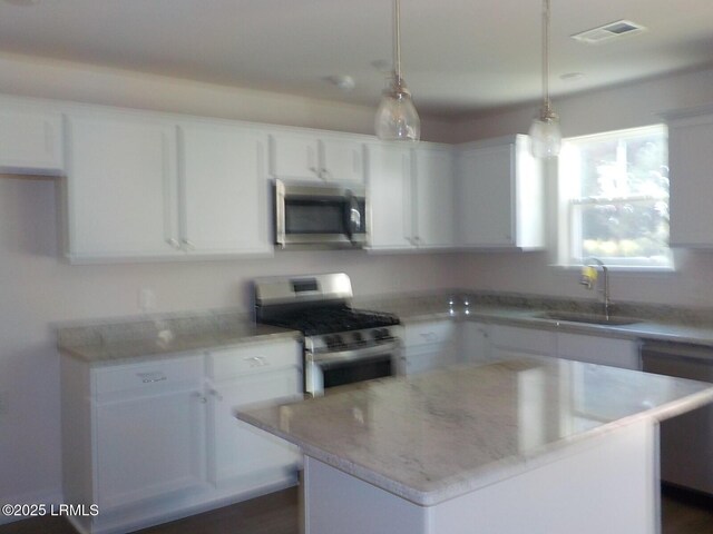 127 Teal Bluff Blvd, Seabrook, SC 29940 - kitchen with stainless steel appliances, white cabinets, hanging light fixtures, and a kitchen island