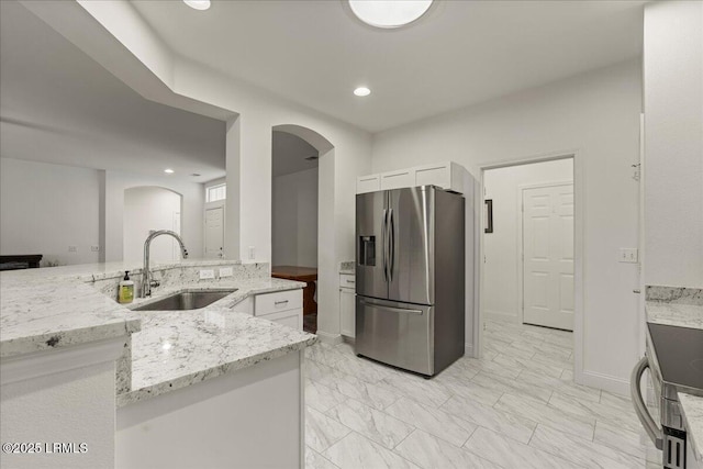 61 Hampton Cir, Bluffton, SC 29909 - kitchen with stainless steel fridge, arched walkways, a sink, white cabinets, and light stone countertops