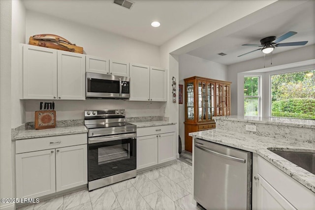 61 Hampton Cir, Bluffton, SC 29909 - kitchen with appliances with stainless steel finishes, light marble finish flooring, a ceiling fan, light stone countertops, and recessed lighting