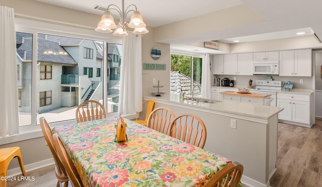 dining space with a chandelier, a tray ceiling, light hardwood / wood-style floors, and sink