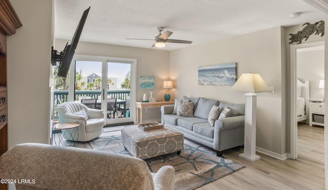 living room with a textured ceiling, light hardwood / wood-style floors, and ceiling fan