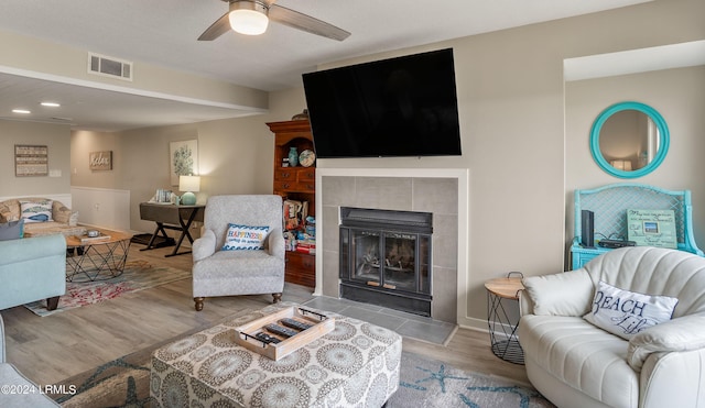 living room featuring ceiling fan, a fireplace, and light wood-type flooring