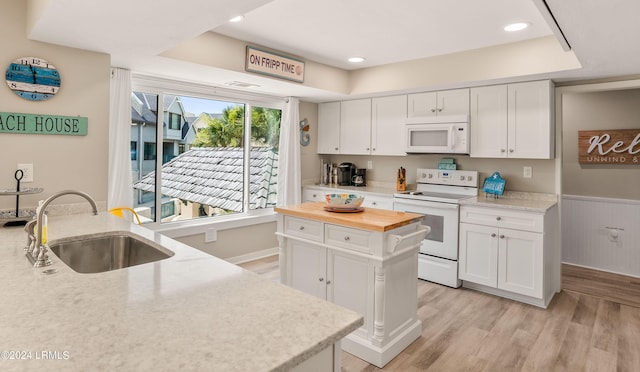 kitchen with sink, light wood-type flooring, white cabinets, a center island, and white appliances