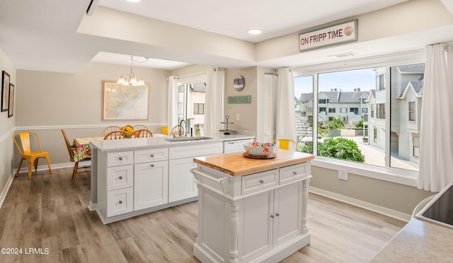 kitchen featuring decorative light fixtures, sink, a kitchen island, and white cabinets