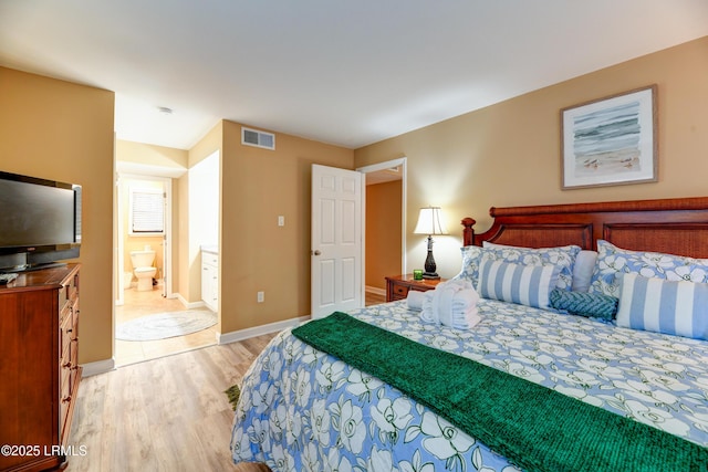 bedroom with connected bathroom and light wood-type flooring