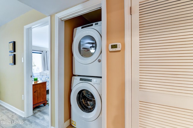 clothes washing area featuring stacked washer and dryer and light hardwood / wood-style flooring