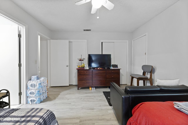 400 William Hilton Pkwy Unit 110, Hilton Head Island, SC 29926 - bedroom featuring multiple closets, light wood-type flooring, a textured ceiling, and a ceiling fan