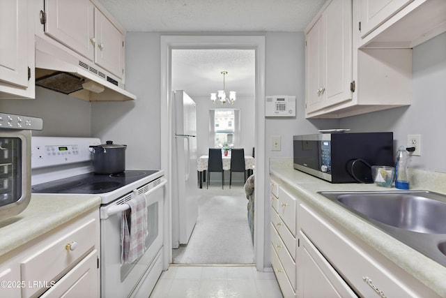 400 William Hilton Pkwy Unit 110, Hilton Head Island, SC 29926 - kitchen with white appliances, under cabinet range hood, a chandelier, light countertops, and a textured ceiling