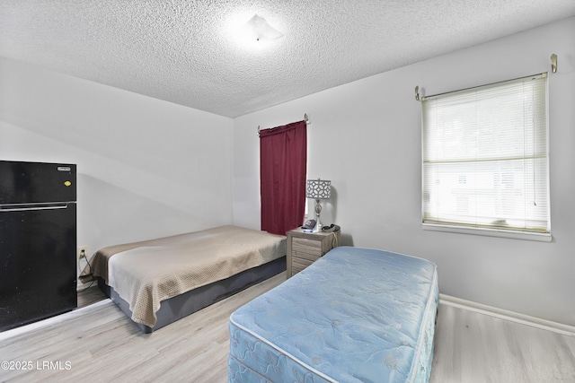 400 William Hilton Pkwy Unit 110, Hilton Head Island, SC 29926 - bedroom with freestanding refrigerator, wood finished floors, and a textured ceiling