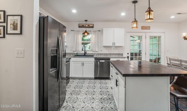 kitchen featuring sink, stainless steel appliances, tasteful backsplash, white cabinets, and decorative light fixtures