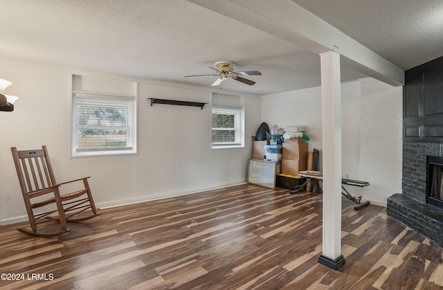 exercise area with a brick fireplace, dark hardwood / wood-style floors, a textured ceiling, and ceiling fan