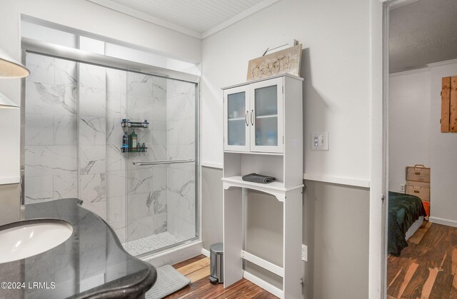 bathroom featuring hardwood / wood-style floors, crown molding, and a shower with door