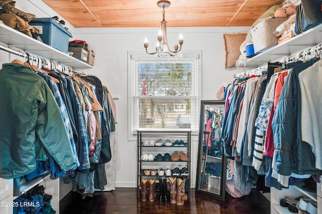 spacious closet with dark wood-type flooring and a chandelier