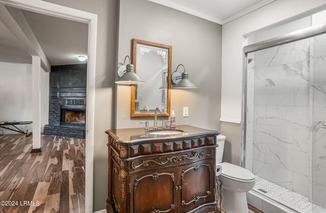 bathroom with vanity, wood-type flooring, a large fireplace, and tiled shower