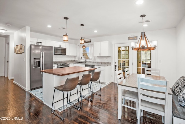 kitchen featuring white cabinetry, stainless steel appliances, a center island, and wooden counters