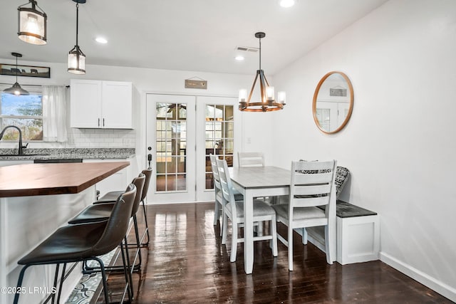 dining area featuring dark hardwood / wood-style flooring, sink, french doors, and a chandelier